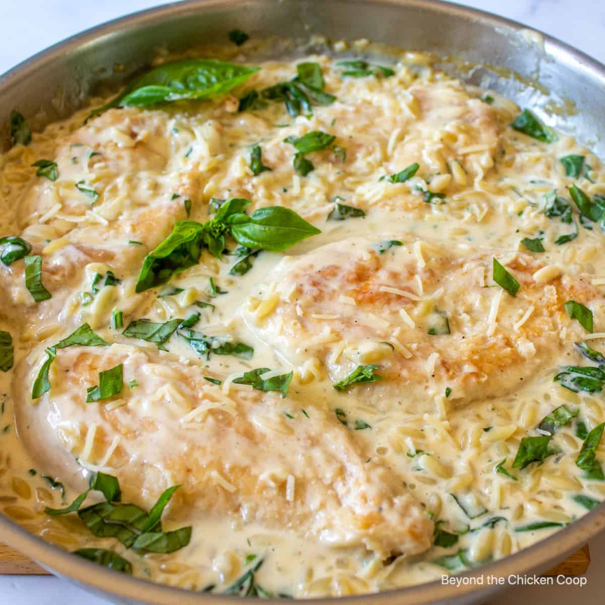 A pan filled with chicken, orzo and spinach.
