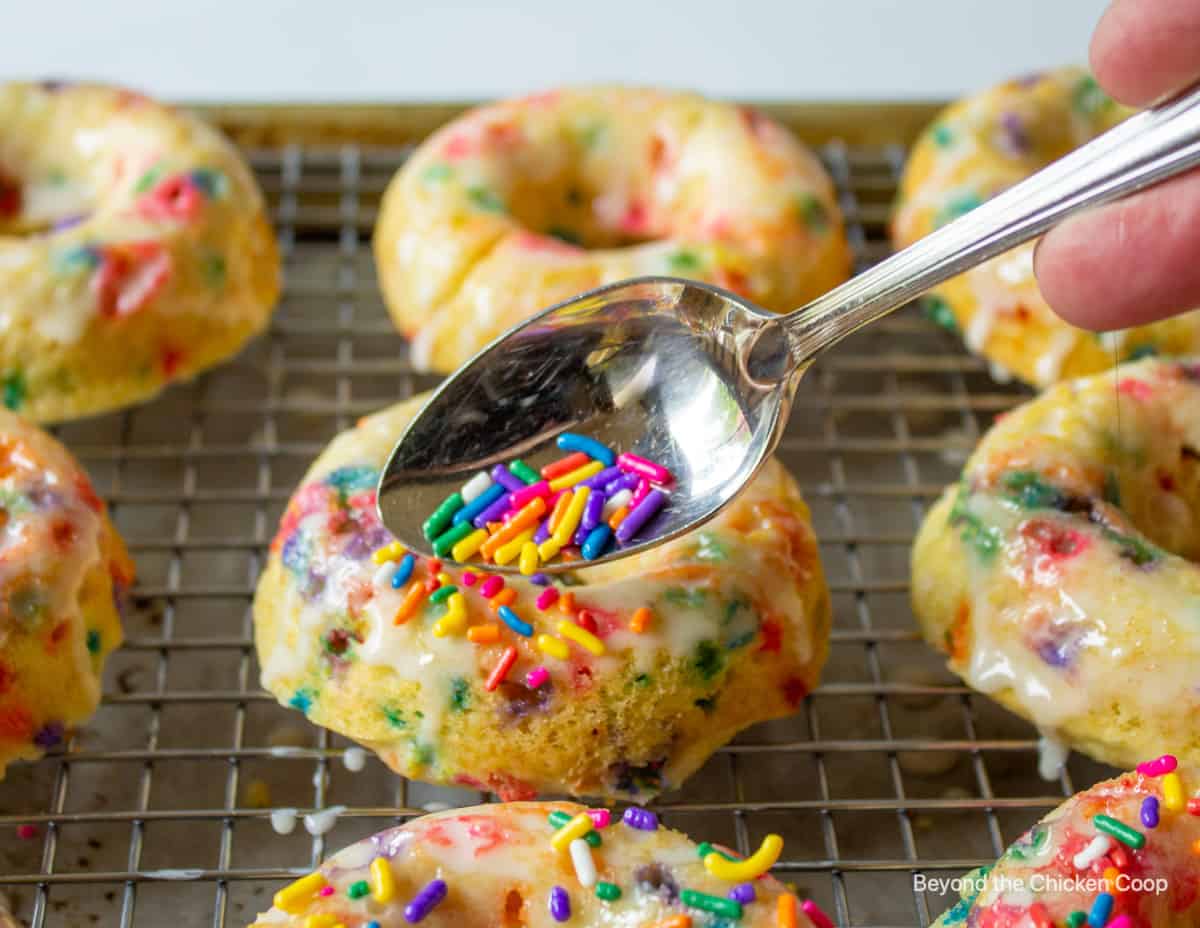 Adding sprinkles to the top of donuts.