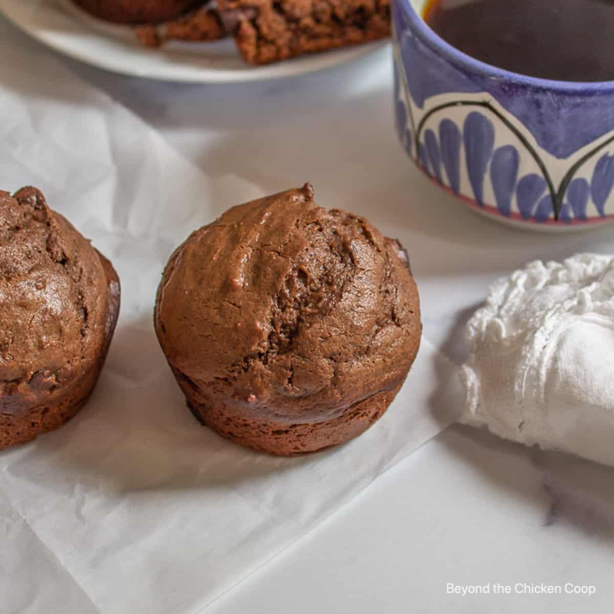 Chocolate muffins next to a cup of coffee.