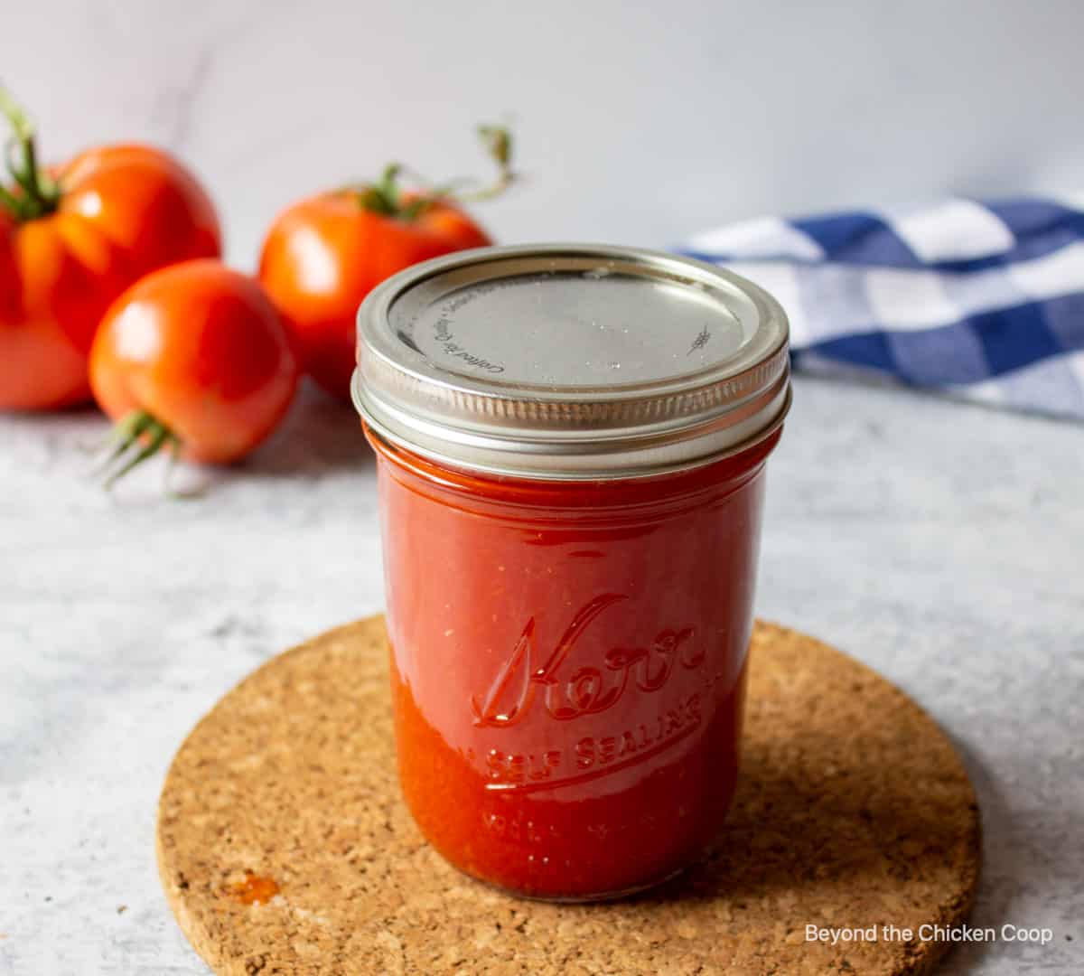 A canning jar filled and a lid and ring on the jar.