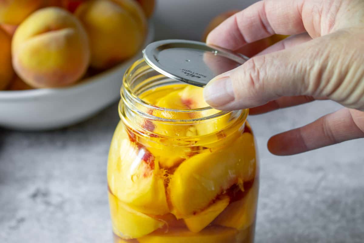 Placing a lid on top of a canning jar.