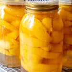 Glass jars filled with yellow peaches.