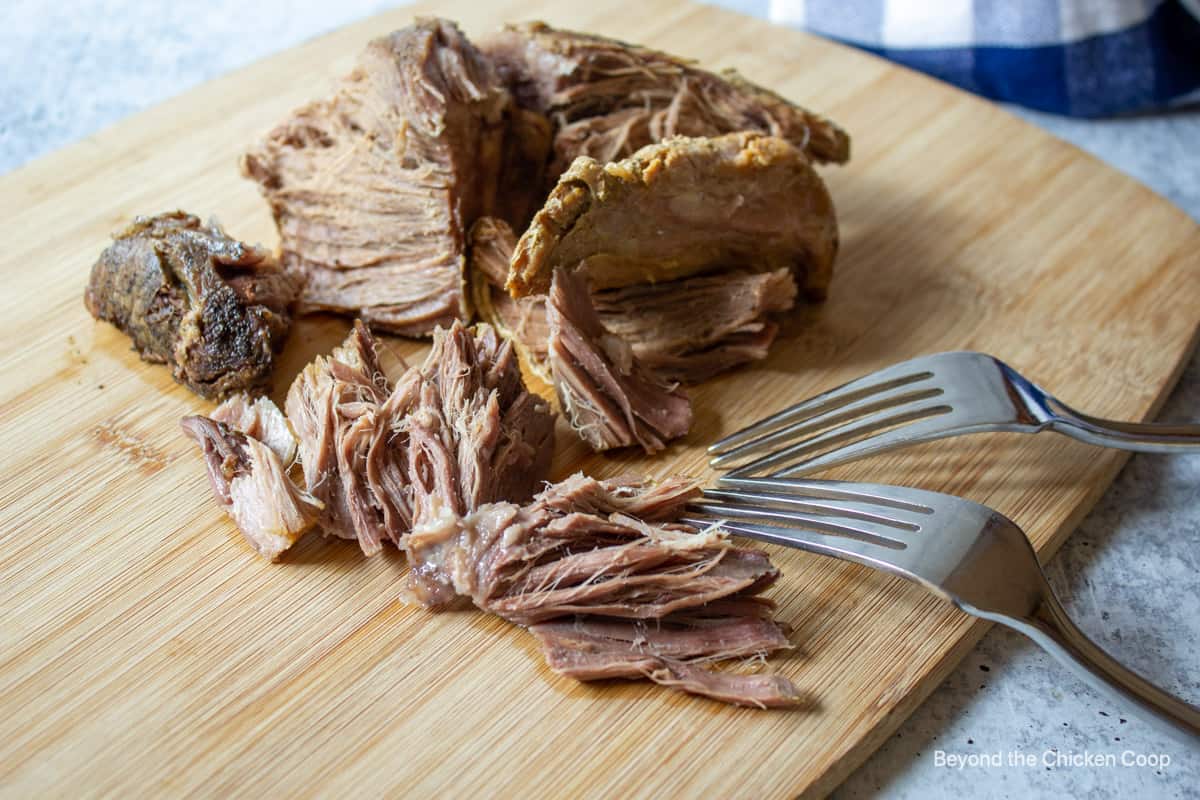 Shredding a cooked roast with two forks.