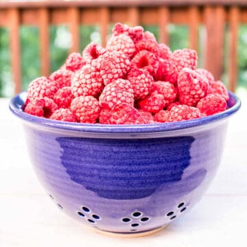 A blue bowl filled with raspberries.