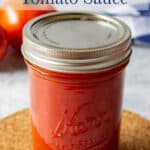 A pint sized jar filled with a red tomato sauce.
