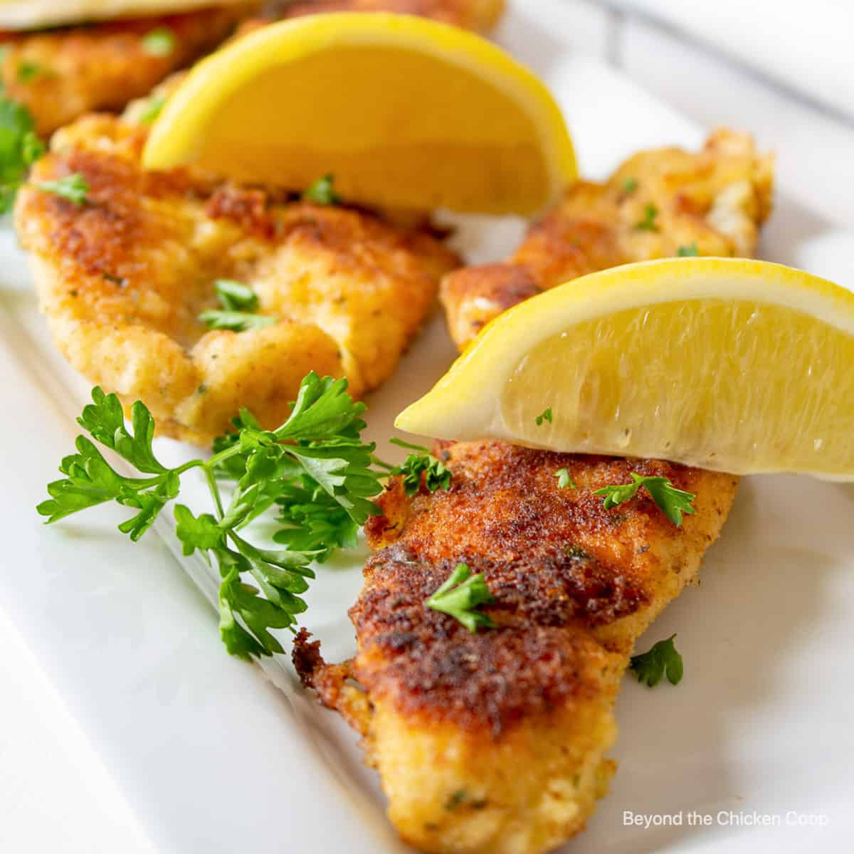 Crispy fish fillets topped with lemon wedges.