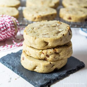 Three pecan cookies stacked on a black coaster.