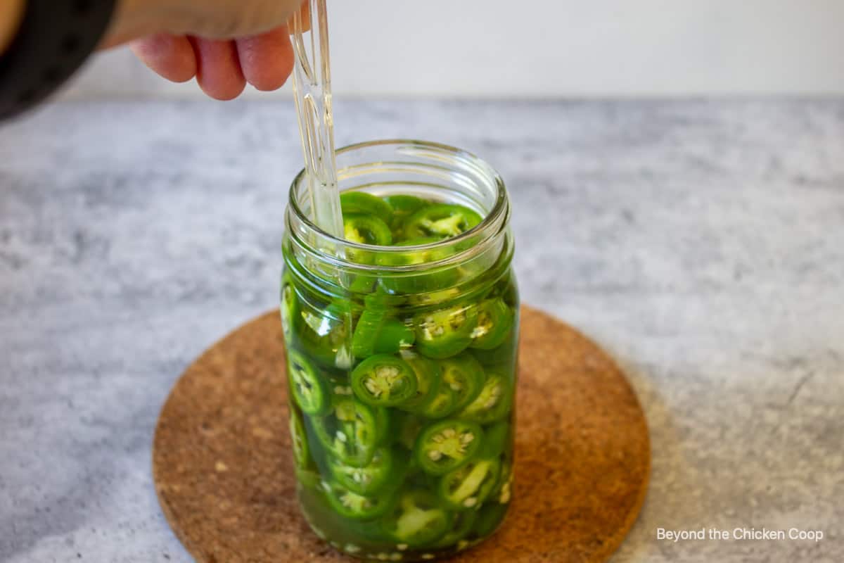 Removing bubbles from a jar of peppers. 