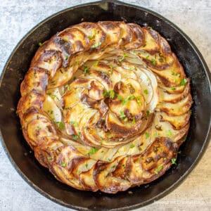 A cast iron skillet filled with thinly sliced potatoes.