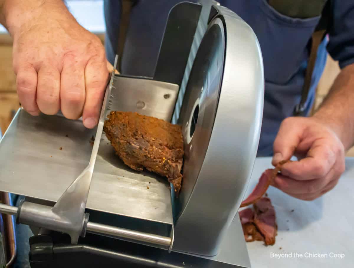 A meat slicer slicing venison pastrami.