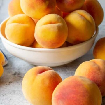 Fresh peaches in a bowl and on a counter.