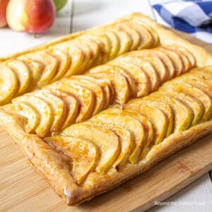 A puff pastry apple tart on a wooden cutting board.