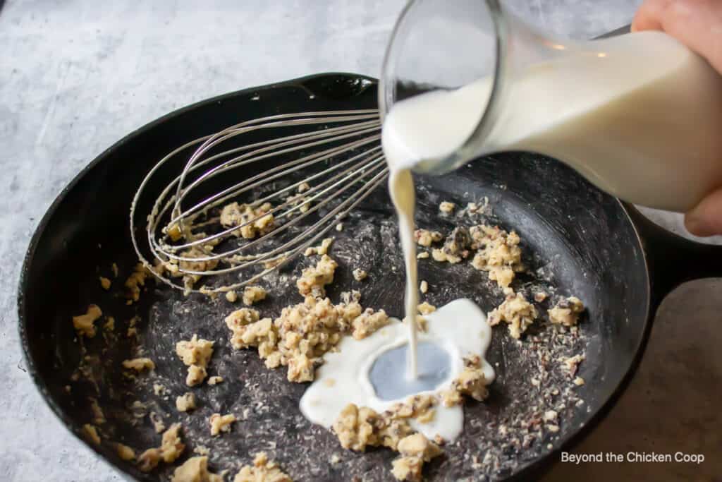 Pouring milk into a pan with a whisk.