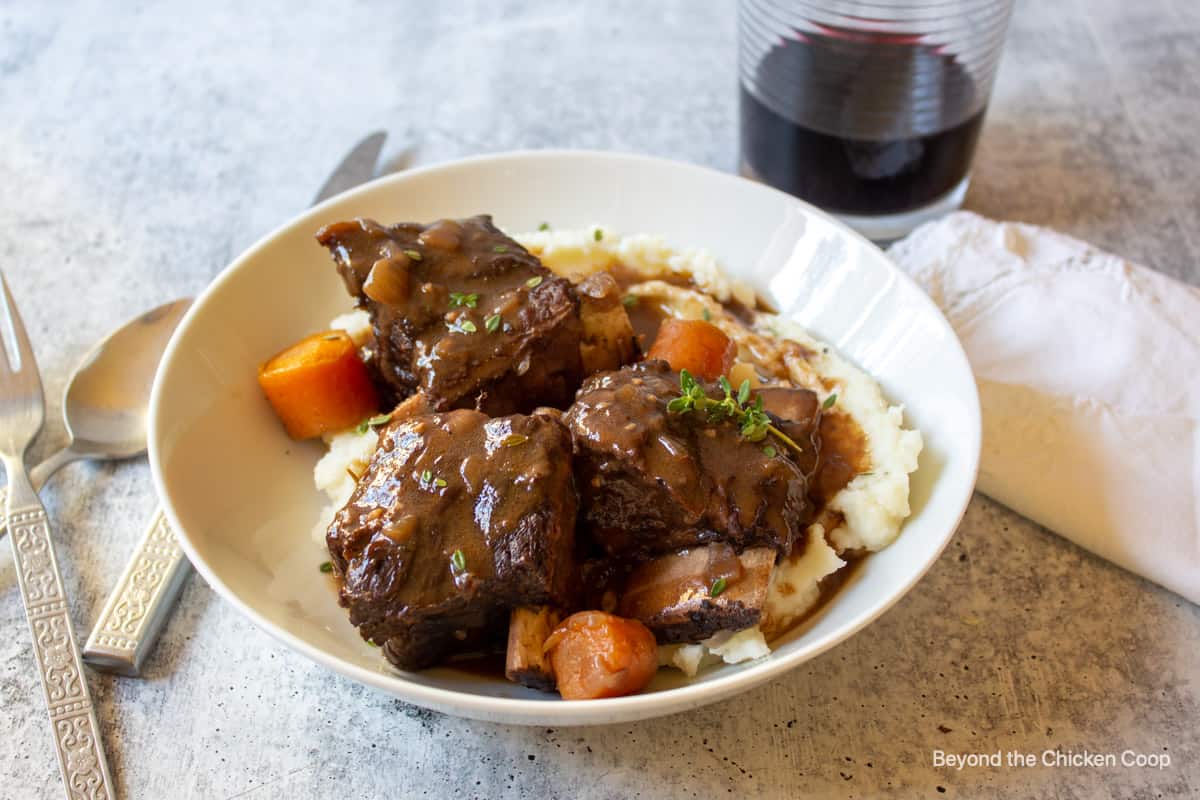 Three beef ribs on top of mashed potatoes.