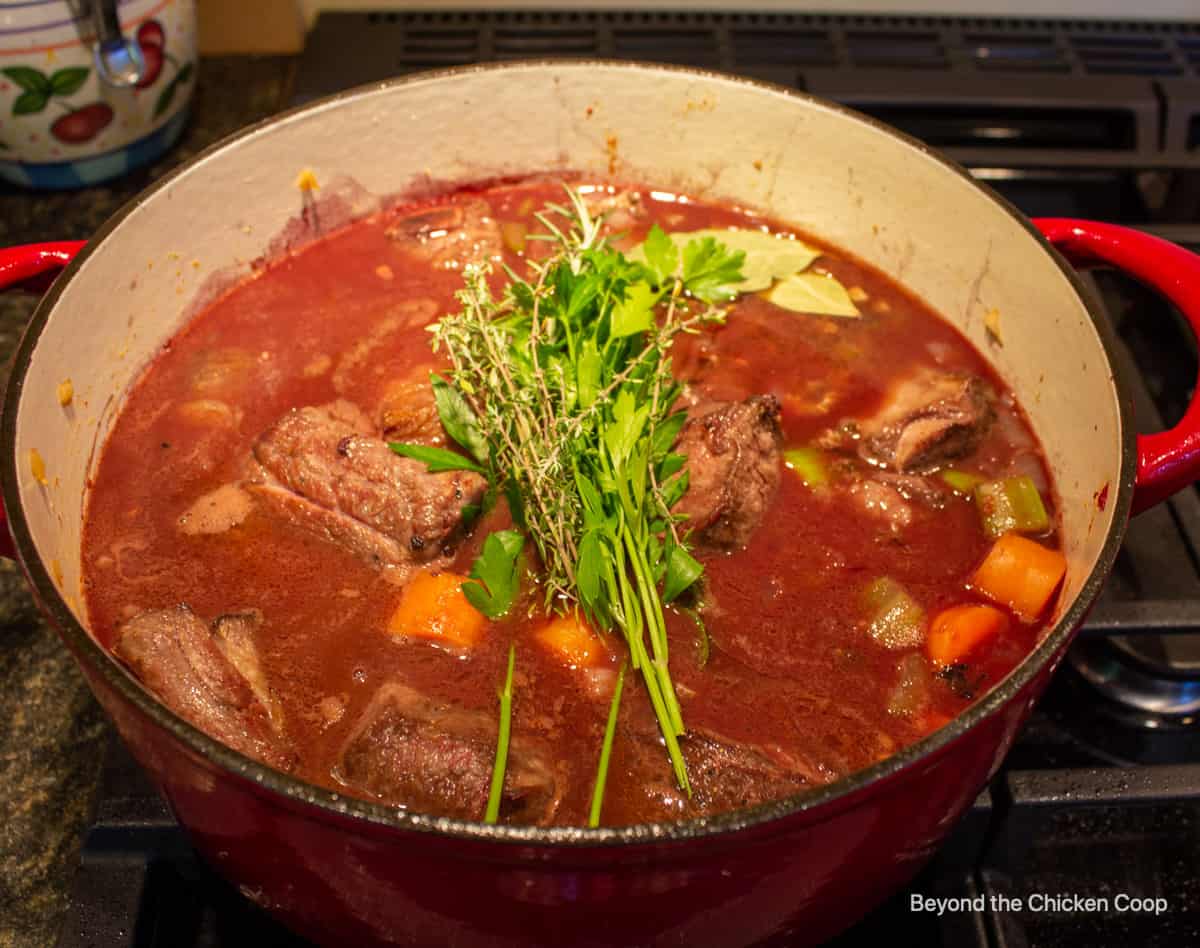 A pot of meat and sauce with fresh herbs.