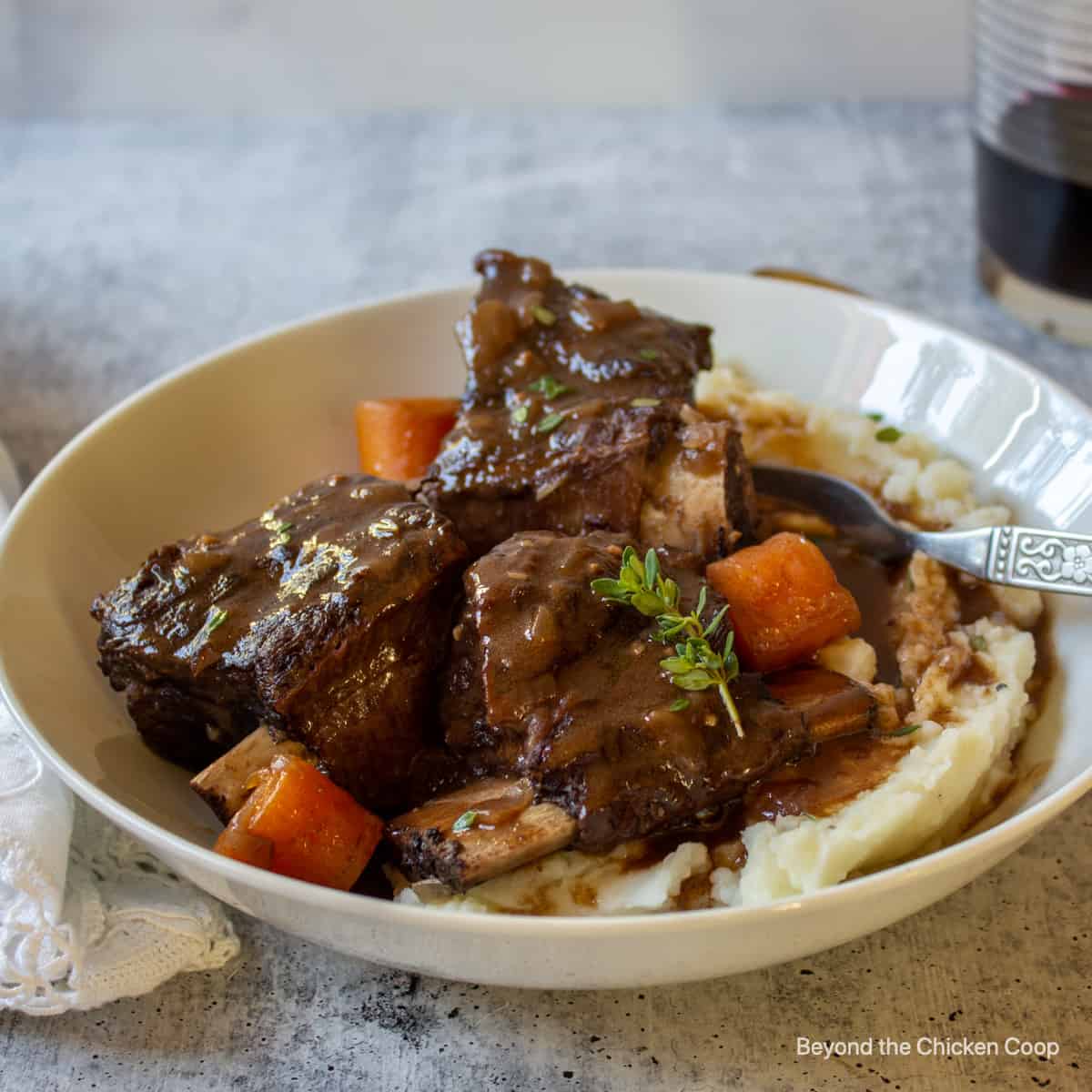 Short ribs on mashed potatoes topped with a brown sauce.