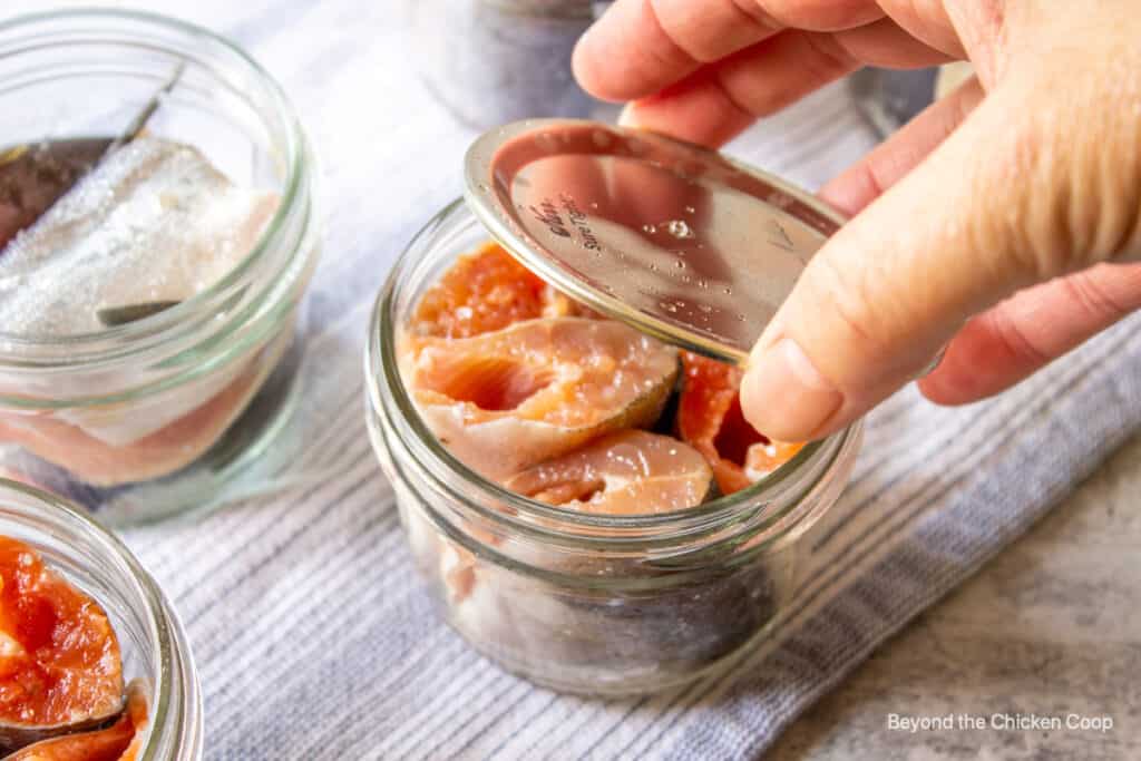 Placing a lid on top of a canning jar.