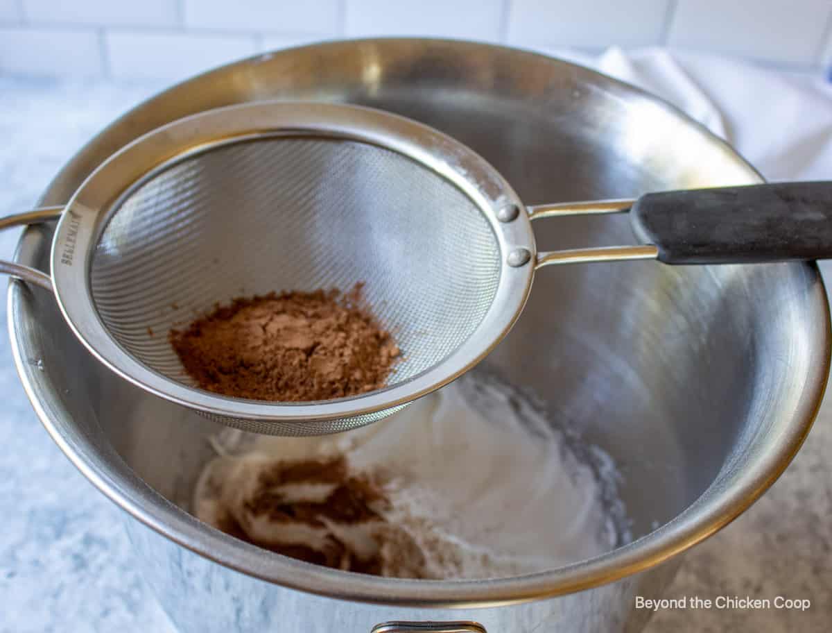 Sifting cocoa powder into a bowl.
