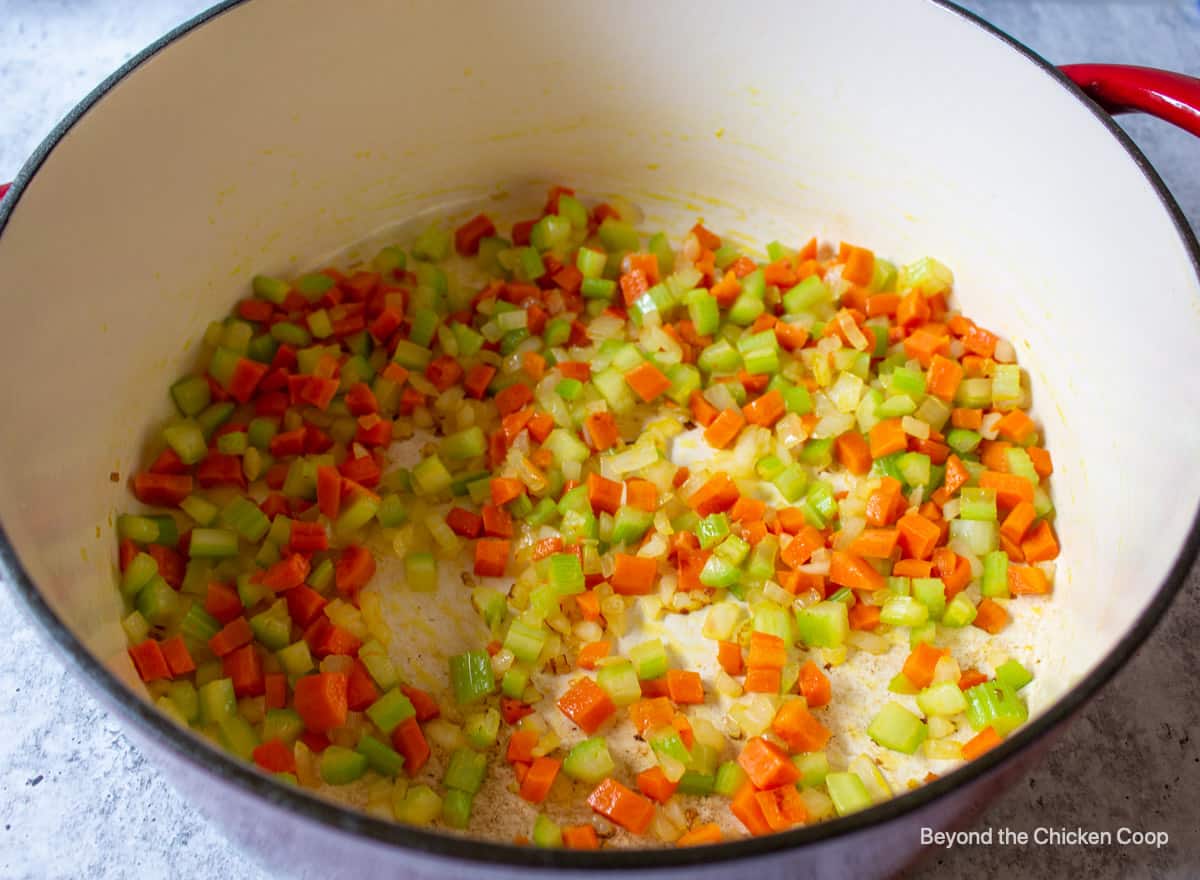 A soup pot with cooked onions, carrots and celery.