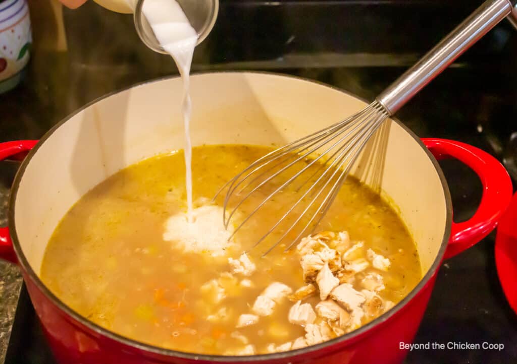 Adding milk to a pot of soup.