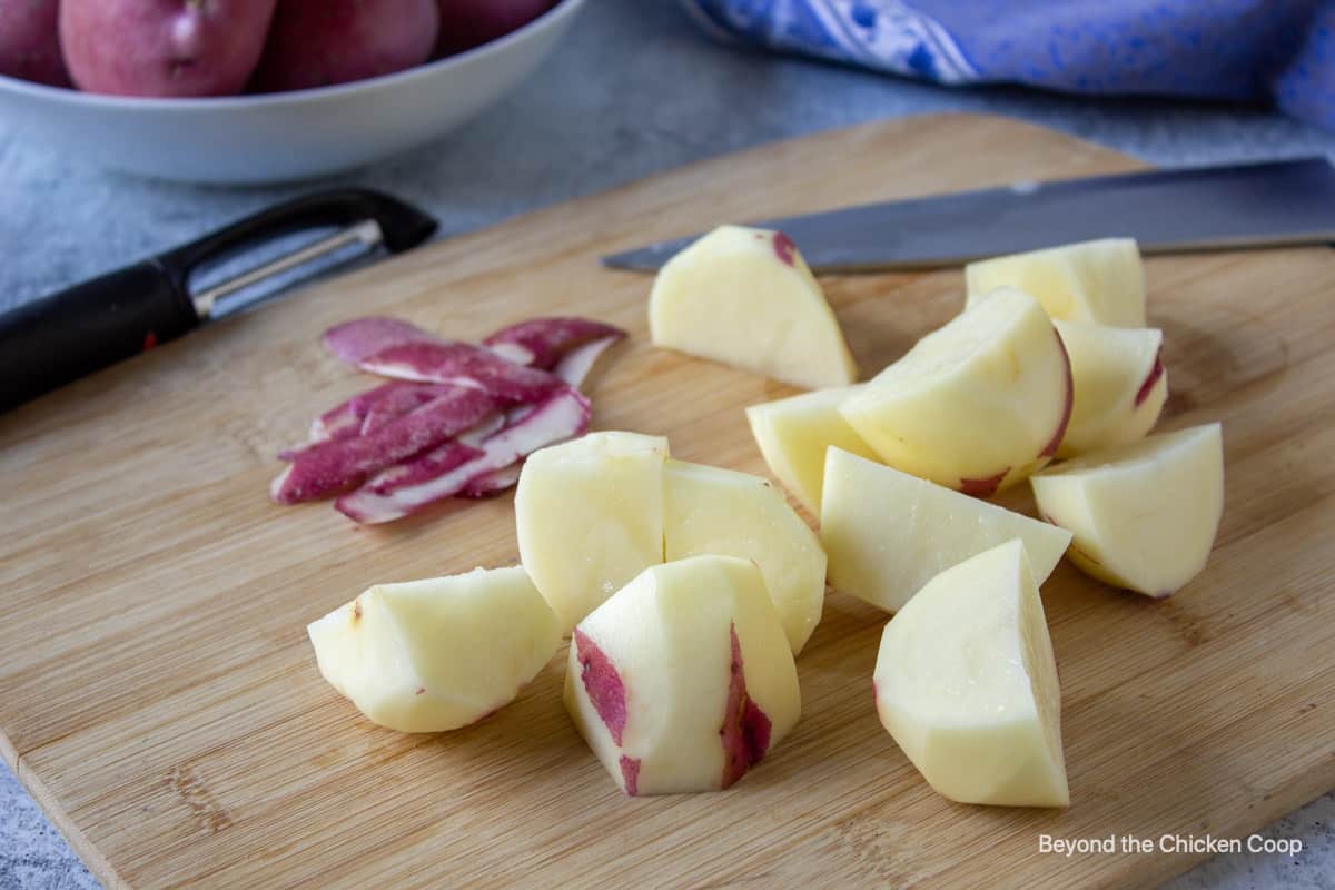 Quartered red potatoes on a cutting board.