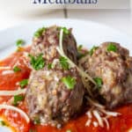 Three meatballs on top of marinara sauce.