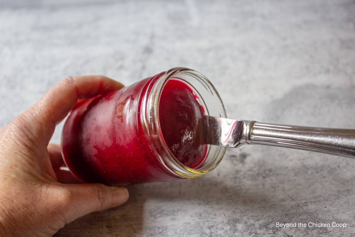 Running a butter knife around the inside of a jar filled with jellied cranberry sauce.