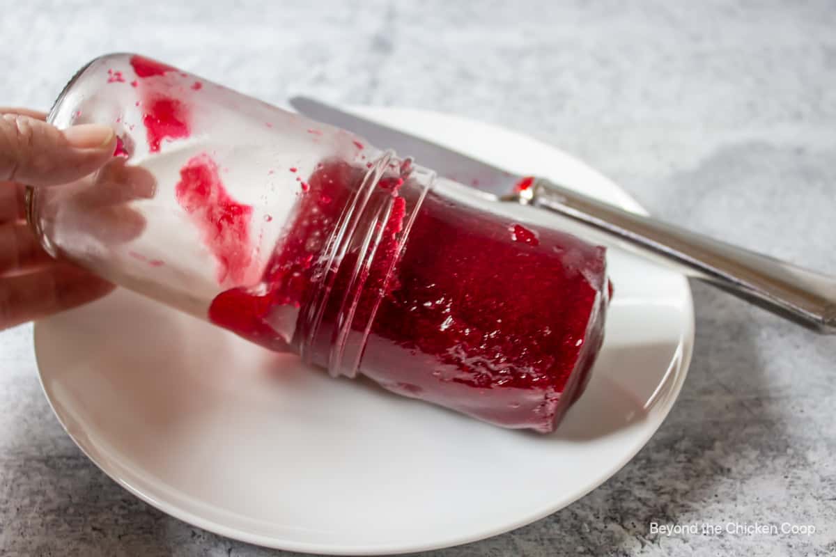 Jellied sauce slipping out of a jar onto a plate.