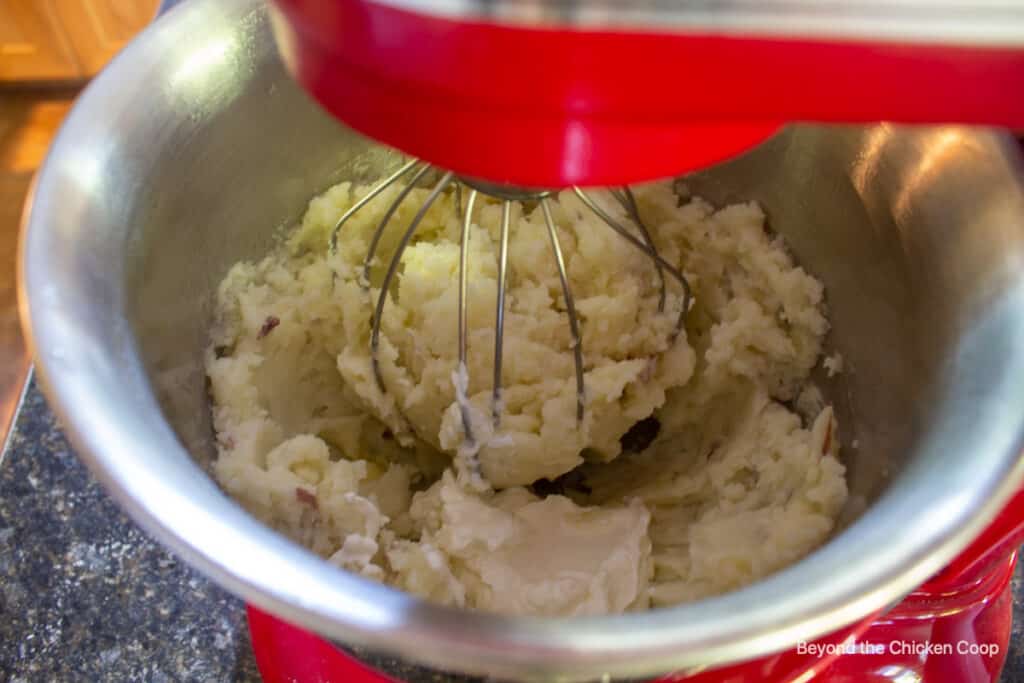 Potatoes being mixed in a mixing bowl.