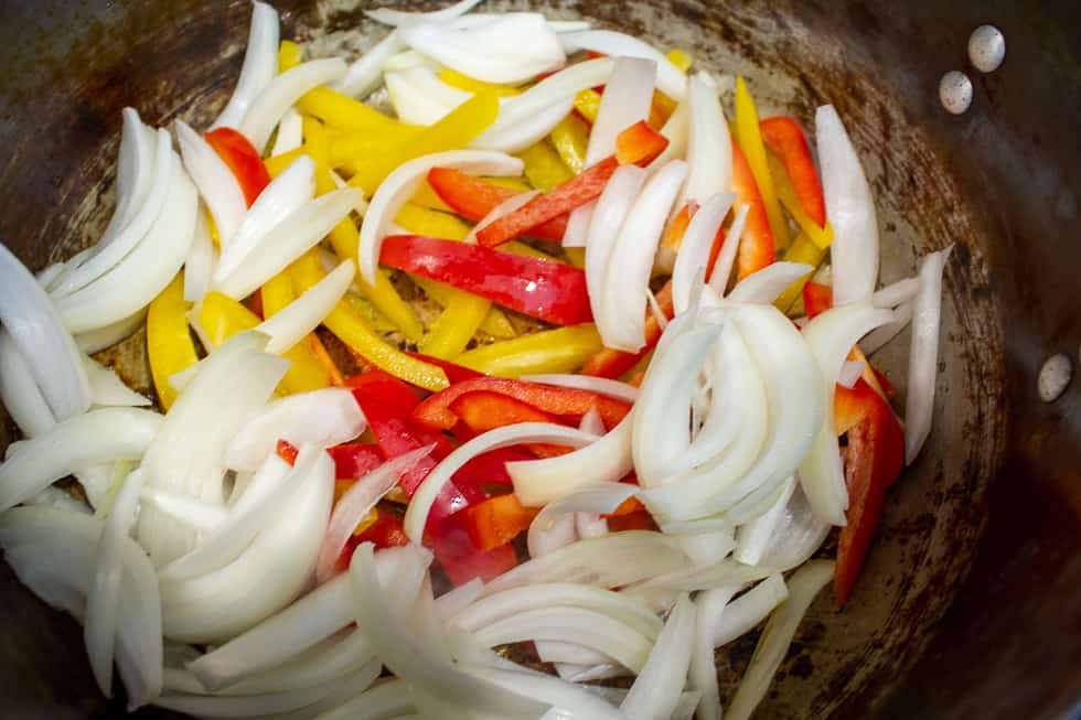 Sliced peppers and onions in a pot.