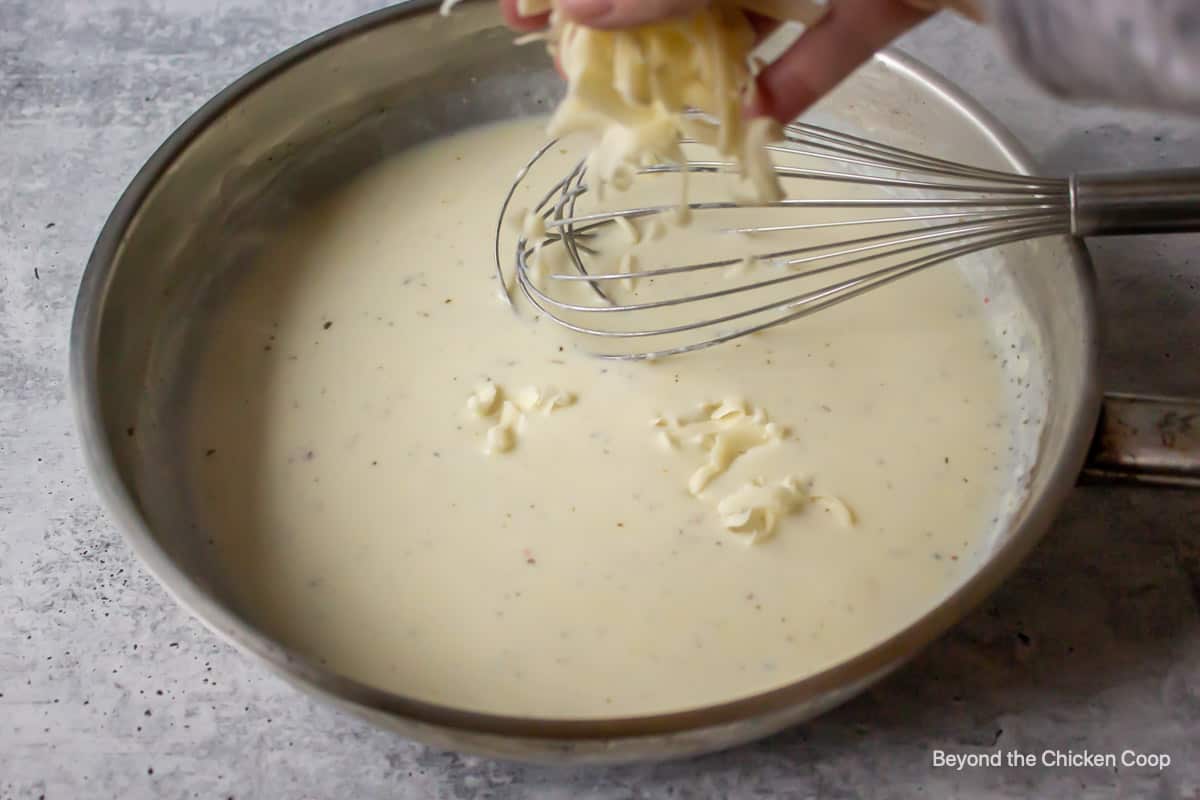 Cheese being sprinkled into a creamy sauce.
