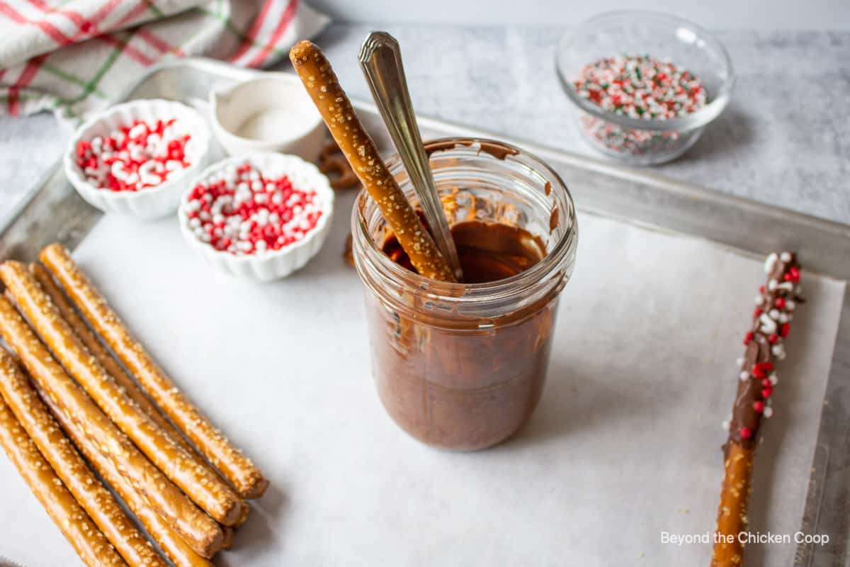 A pretzel in a glass with melted chocolate.