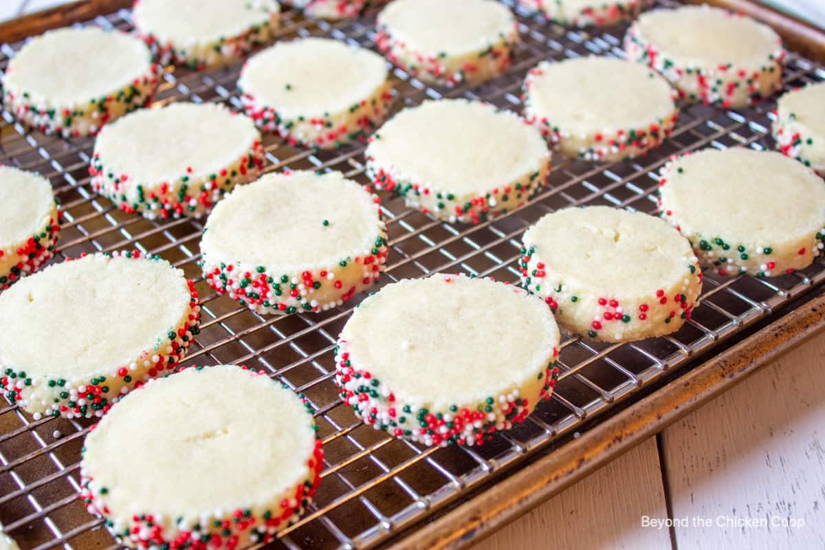 A baking rack with cookies with sprinkles.