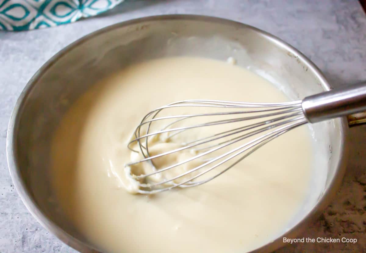 A thick white sauce with a whisk.