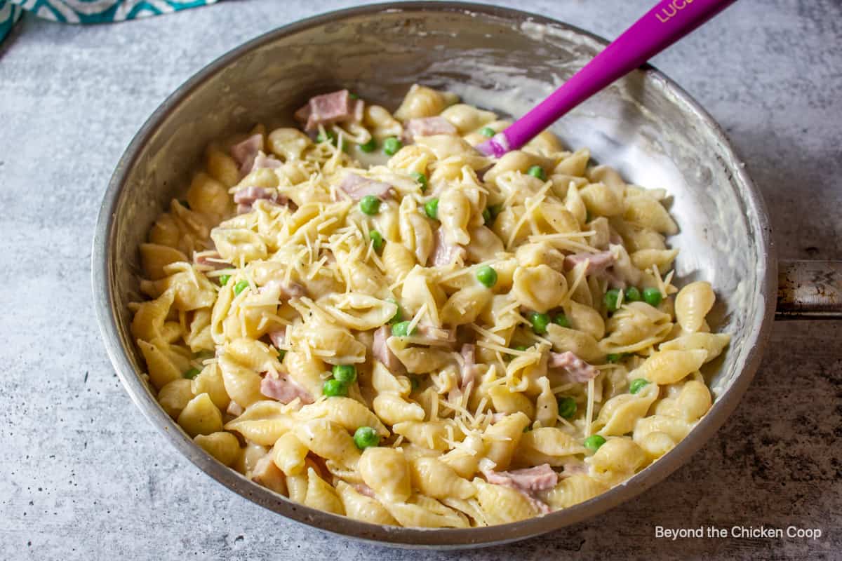 A pasta dish with ham and peas.