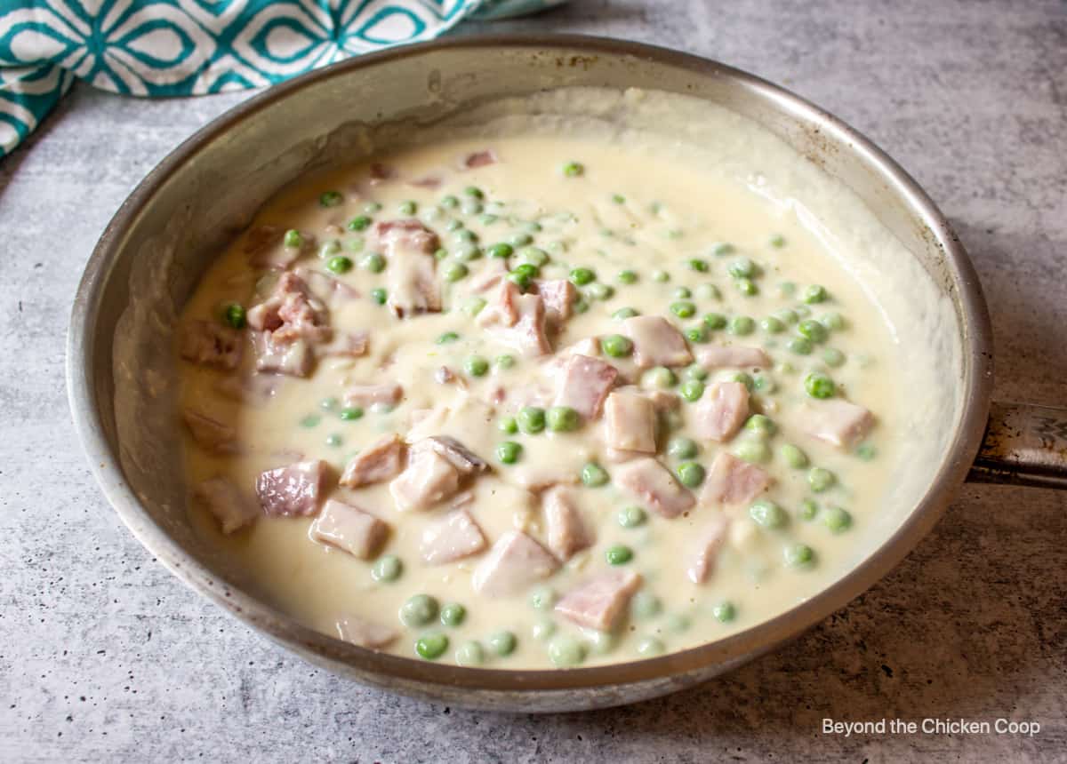 A creamy white sauce with ham and peas.