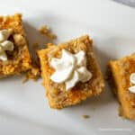 Pumpkin bars topped with a dollop of whipped cream.