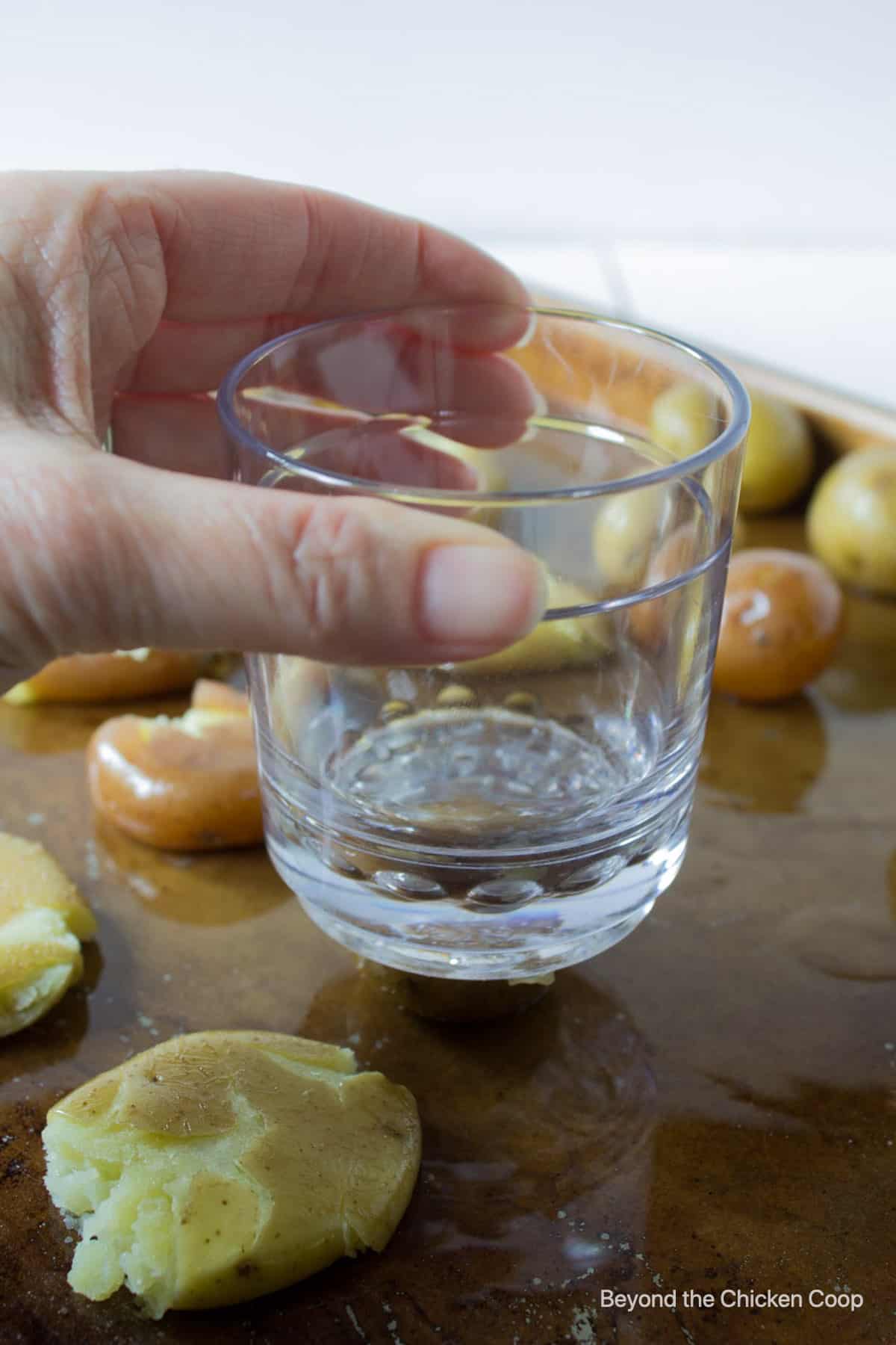 Using a cup to smash cooked potatoes.