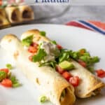 Two flautas on a plate topped with tomatoes and cilantro.