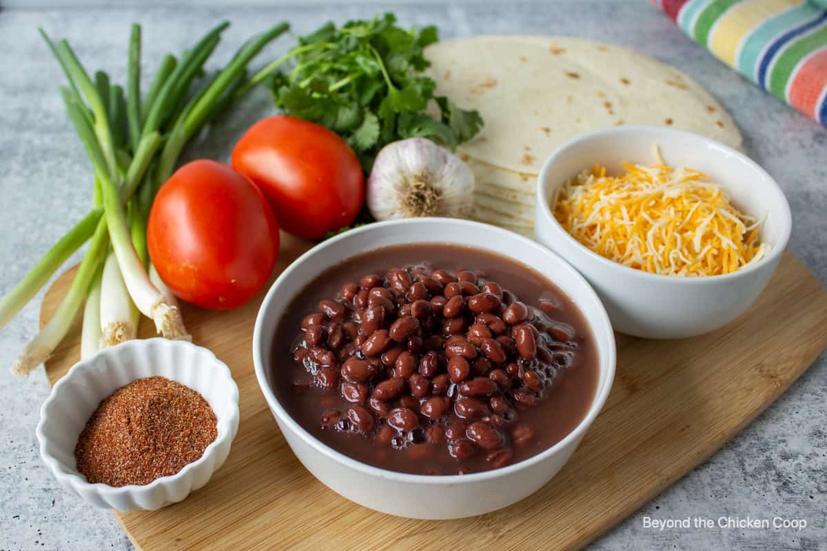 Small bowls filled with black beans, cheese and taco seasoning. 