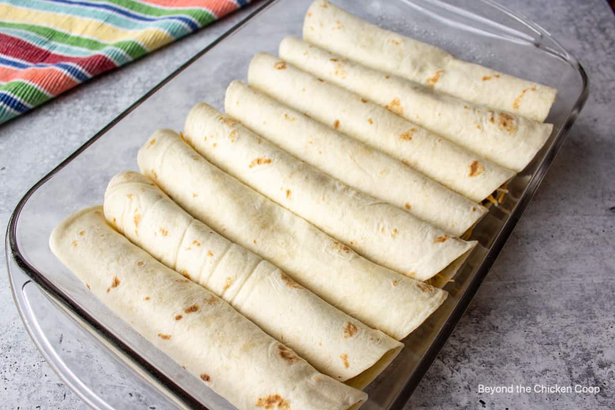 Rolled tortillas in a baking dish.