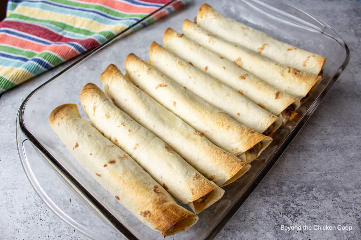 Baked flautas in a glass casserole dish.