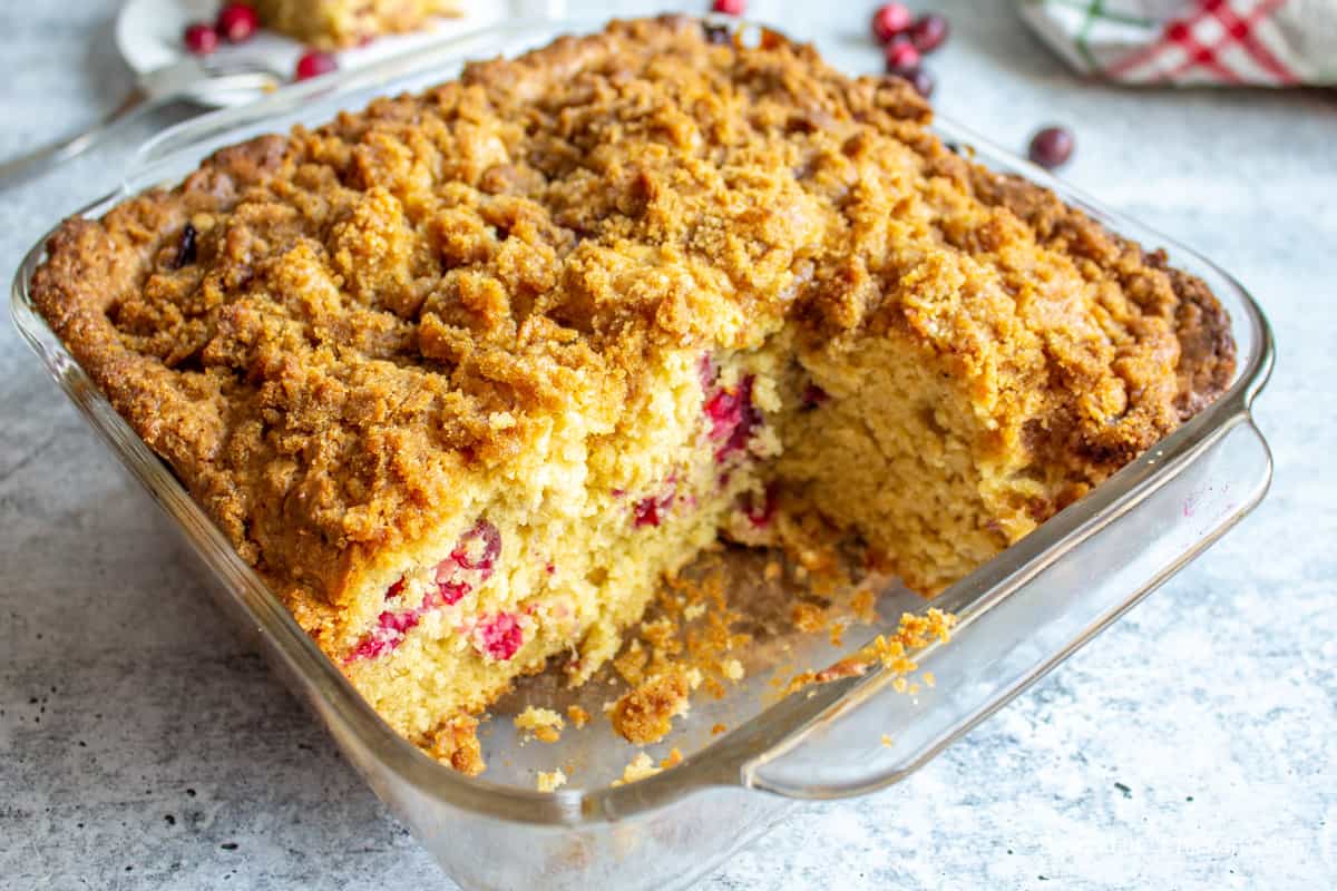A cut coffee cake filled with red berries.