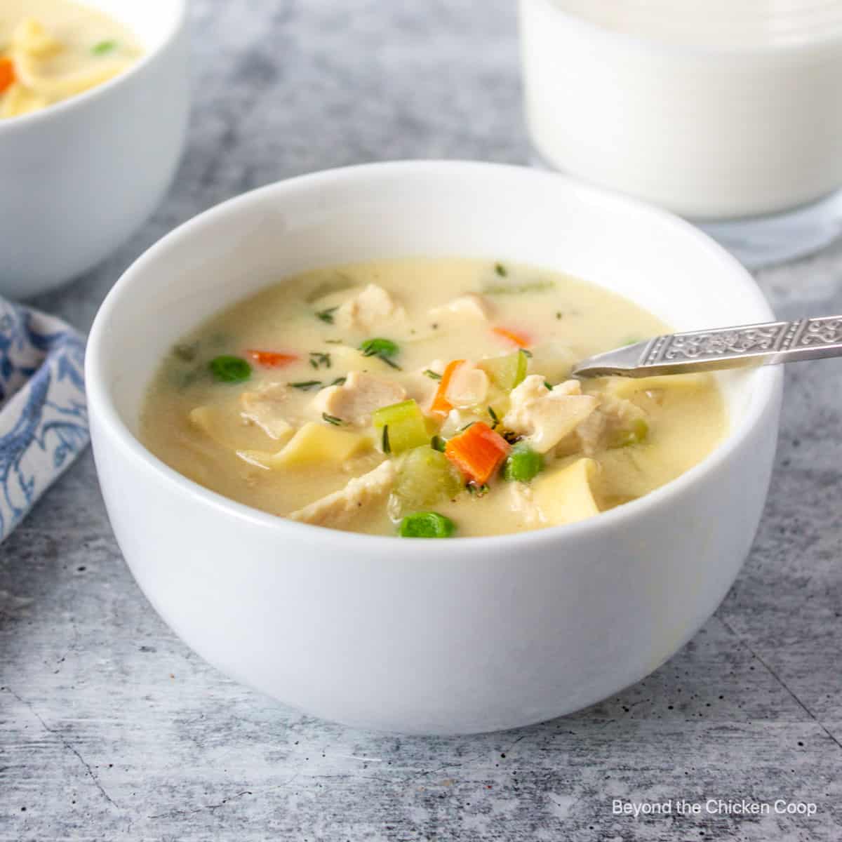 A bowl of creamy chicken noodle soup with veggies.