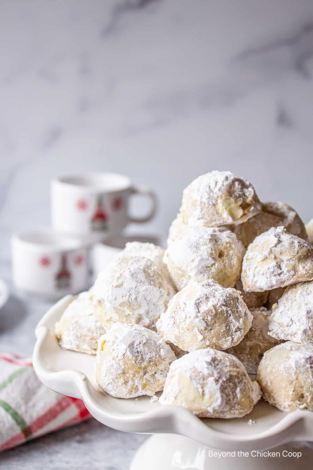 Small round cookies covered with powdered sugar on a cake stand.