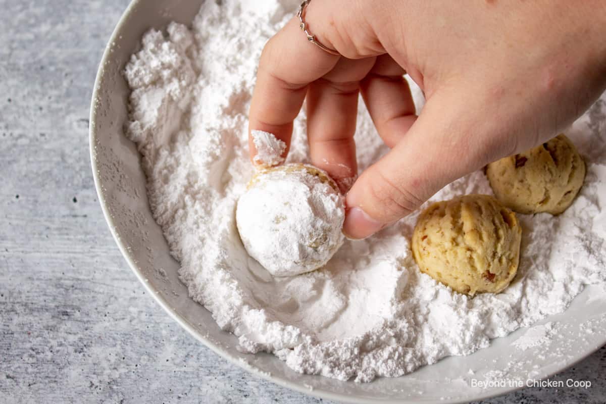Rolling a round cookie in powdered sugar.