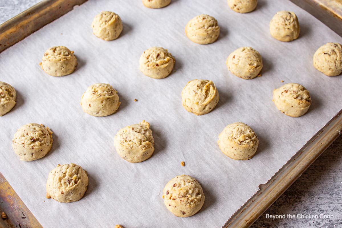 A cookie sheet filled with balls of cookie dough.
