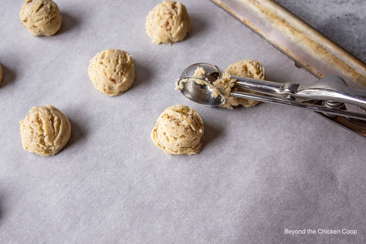 Forming balls of cookie dough with a small scoop.