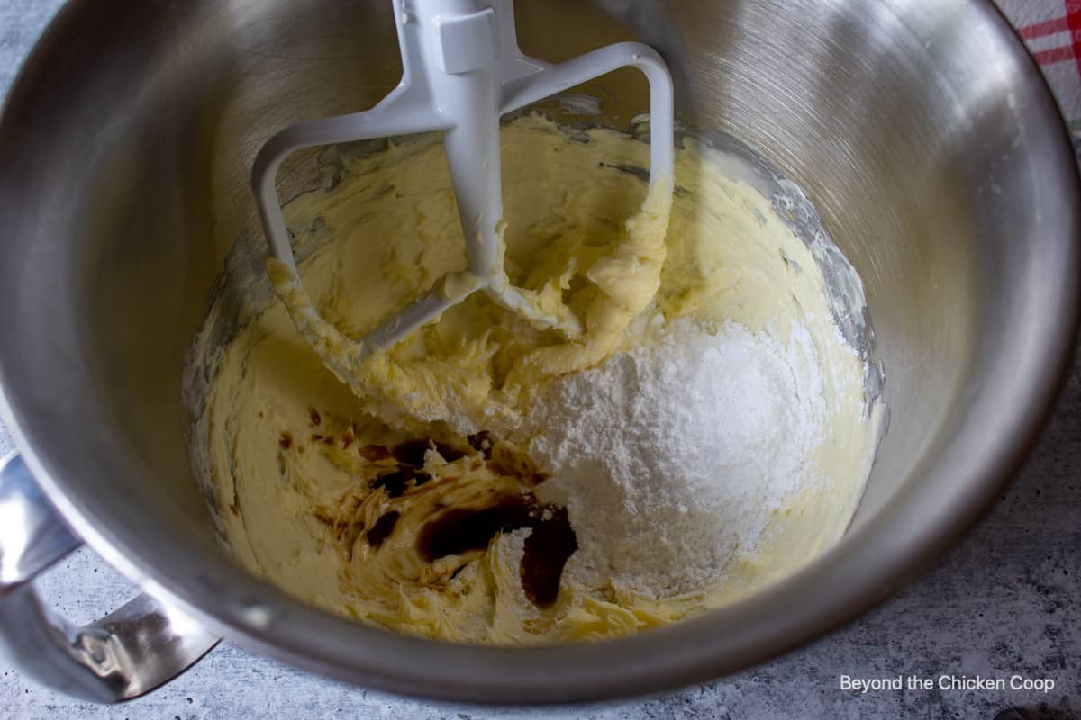 Powdered sugar in a mixing bowl with creamy butter.