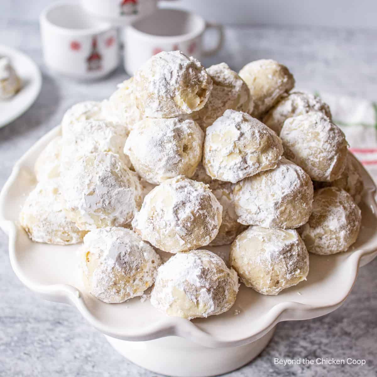 A cake stand filled with snowball cookies.